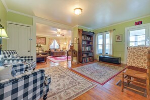 A living room with a checkered sofa, a wooden bookshelf, and a patterned rug. - Hike, Explore & Unwind: Finger Lakes B&B Suite (Interlaken)