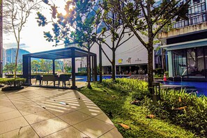 An outdoor area with a covered seating area, a pool, and a building with a sign. - Sky Loft at Midhills Genting by HCK (Genting Highlands)
