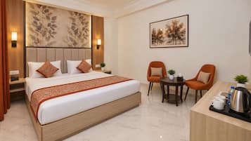 A hotel room with a large bed, two chairs, a small table, and a desk with a coffee maker.