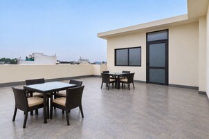 Una terrazza sul tetto con tavolo e sedie, una porta e vista sulla città.