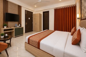 A hotel room with a bed, a desk, a television, and a wardrobe.