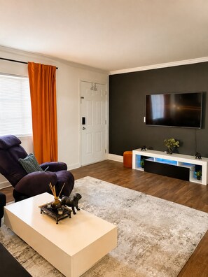 A modern living room with a sofa, a coffee table, a flat-screen TV, and a console table with decorative items.