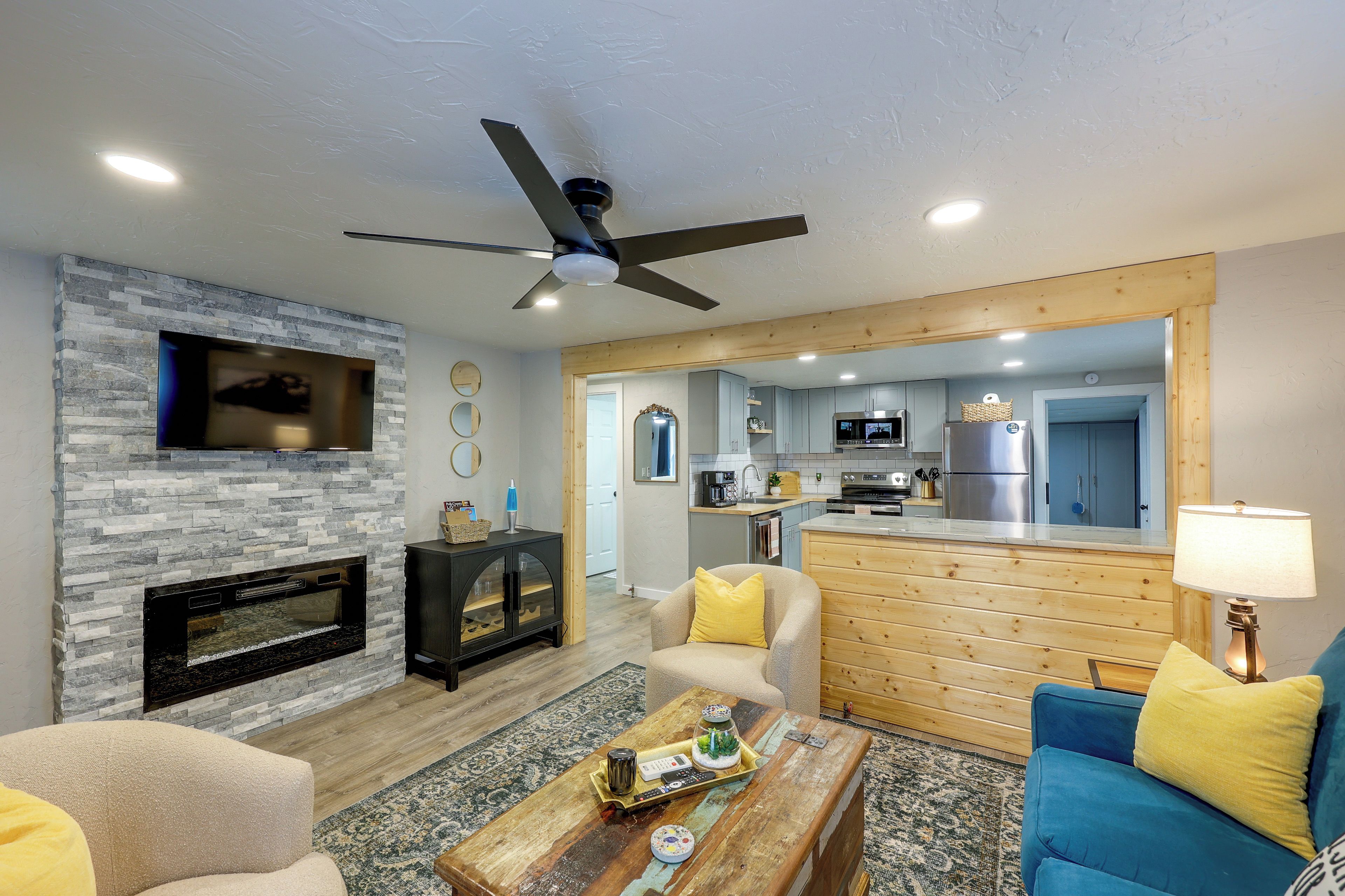 A modern living room with a fireplace, a dining area, and a kitchen with wooden accents.