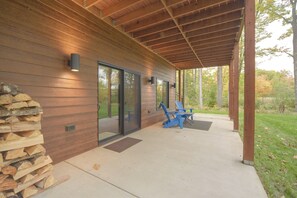 A covered outdoor area with a wooden deck, a stone wall, and a stack of firewood. - Cozy Lakefront Retreat w/ Patio on the Big Chip (Hayward)