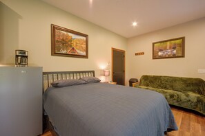 Ein Schlafzimmer mit einem Bett, einem grünen Sofa, einer Kaffeemaschine und zwei gerahmten Bildern an der Wand.