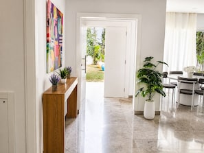 A hallway with a wooden console table, a potted plant, and a door leading to a garden. - Luxurious Villa in Gammarth, Tunisia with Private Pool (Gammarth)