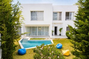A modern two-story house with a swimming pool, surrounded by greenery and two bean bags. - Luxurious Villa in Gammarth, Tunisia with Private Pool (Gammarth)