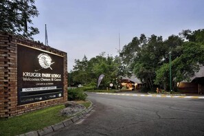 A brick wall with a sign for Kruger Park Lodge, including a logo, welcome message, and information about an owl show. - Kruger Park Lodge unit 84 (Ehlanzeni District Municipality)