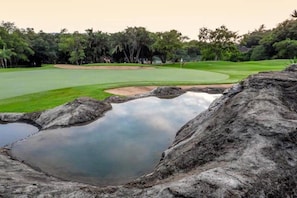 A golf course with a pond, trees, and a rock formation. - Kruger Park Lodge unit 84 (Ehlanzeni District Municipality)