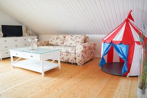 A room with a sofa, a glass-top table, a white dresser, and a red and white tent-like structure. - by the lake with private beach, fireplace and sauna (Löbnitz)