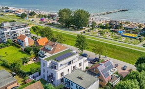 Ein Wohngebiet mit modernen Häusern, einem Solarpaneel auf einem Dach und einem Steg, der ins Wasser führt.