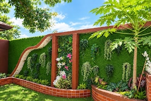 A landscaped garden with a brick wall, green foliage, and a variety of plants. - Romantic Love Nest Dome Retreat at Pebble Walk Beach Resort (Romblon)