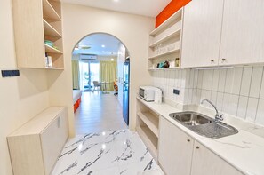 A modern kitchen with a marble floor, a built-in sink, and a microwave. - Near Beach Condo with Pool Access in Pattaya City (Pattaya City)