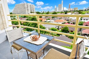 A balcony with a table, chairs, and a view of a cityscape. - Near Beach Condo with Pool Access in Pattaya City (Pattaya City)