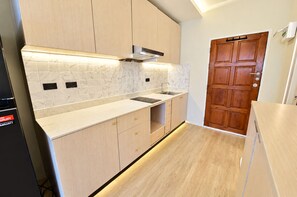 Een moderne keuken met lichte houten kastjes, een marmeren spatwand en een ingebouwde oven.