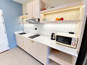 A modern kitchen with white cabinets, a built-in microwave, and a stainless steel kettle. - Minutes from the Beach apartment in Pattaya (Pattaya City)