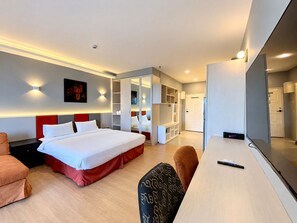 A modern hotel room with a bed, seating area, and a desk with a remote control. - Minutes from the Beach apartment in Pattaya (Pattaya City)