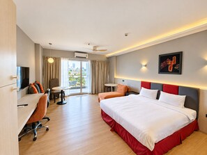 Ein Hotelzimmer mit Bett, Schreibtisch, Stuhl und Blick auf die Stadt.
