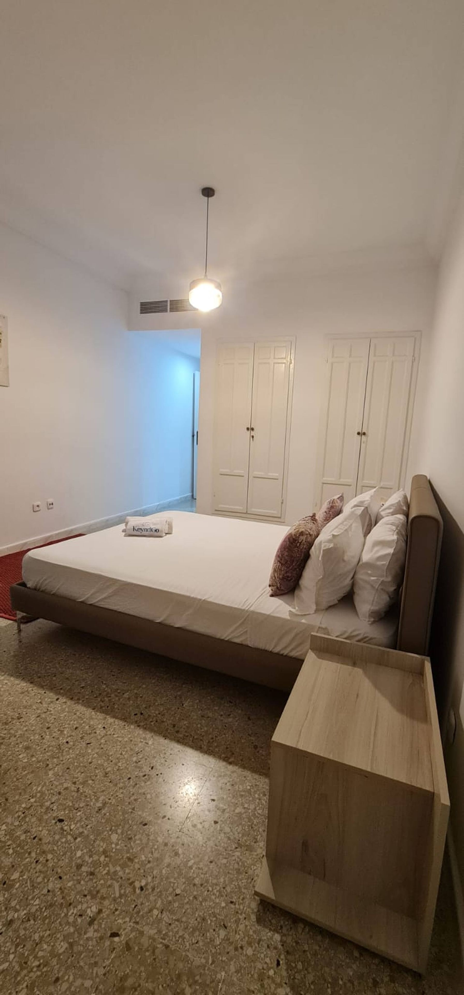 Une chambre à coucher comprenant un lit, une table de chevet, une armoire et un luminaire au plafond.