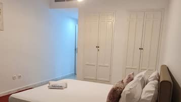 Une chambre à coucher comprenant un lit, une table de chevet, une armoire et un luminaire au plafond.