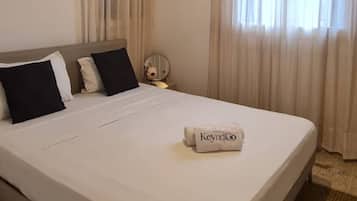Hotellihuone, jossa on sänky, pyöreä pöytä ja riippuvalaisin.