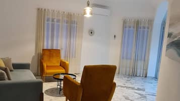A modern living room with a sofa, armchairs, a coffee table, and a marble floor.