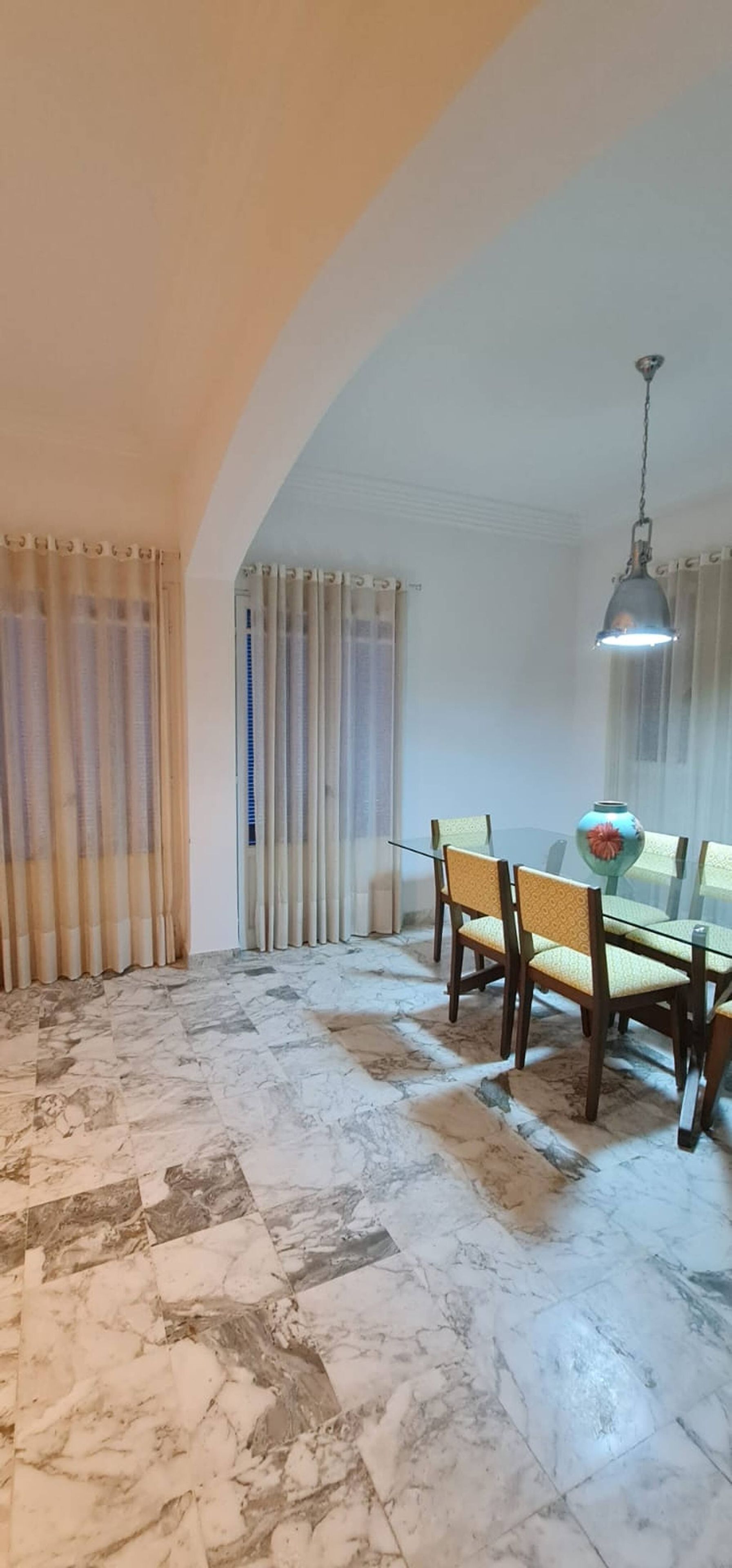 Een eethoek met een glazen tafel, stoelen en een hanglamp.