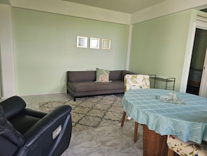 Sala de estar com sofá, mesa de jantar com toalha e tapete estampado.