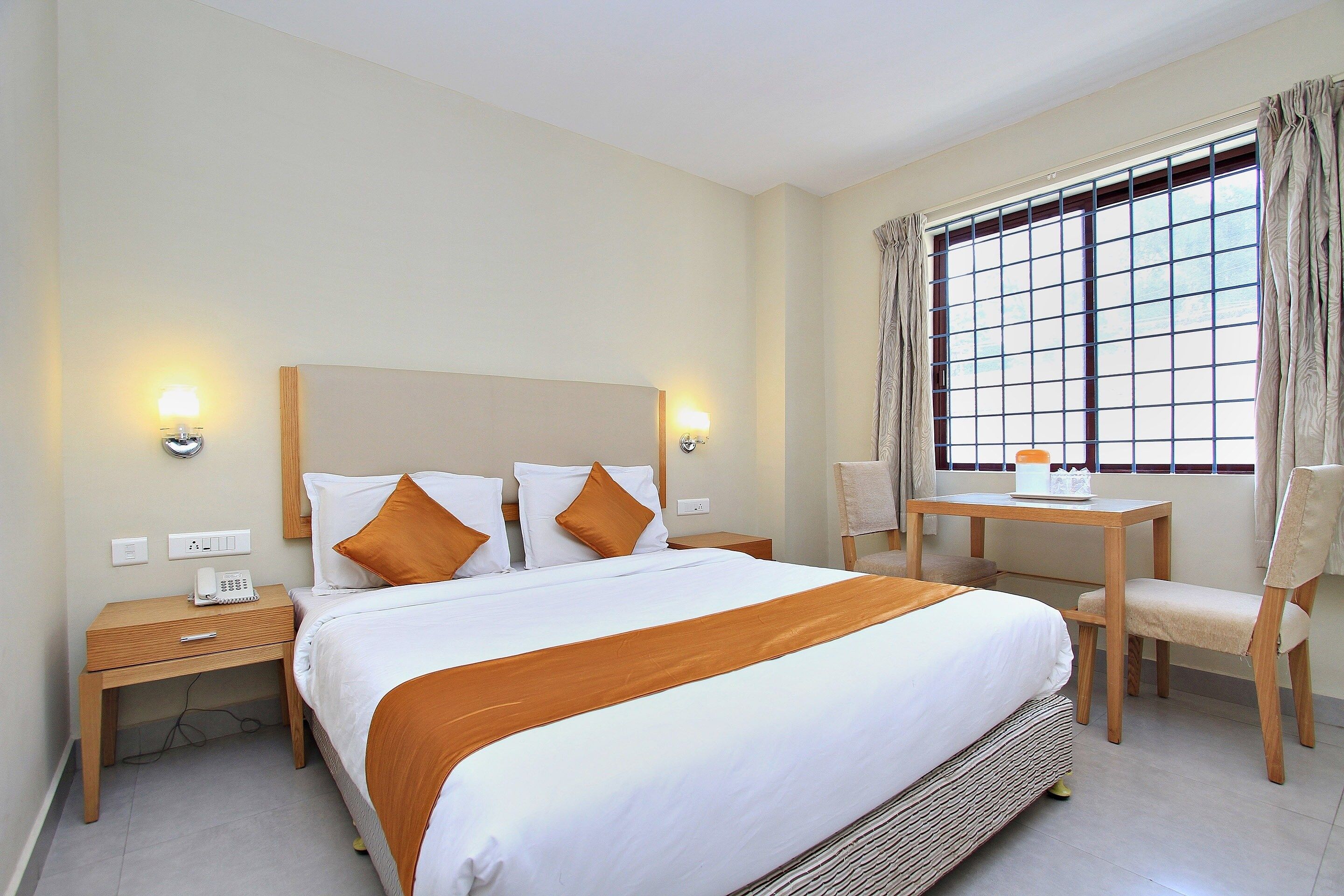 A hotel room with a large bed, bedside tables, a desk, and a chair.
