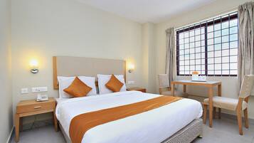 A hotel room with a large bed, bedside tables, a desk, and a chair.