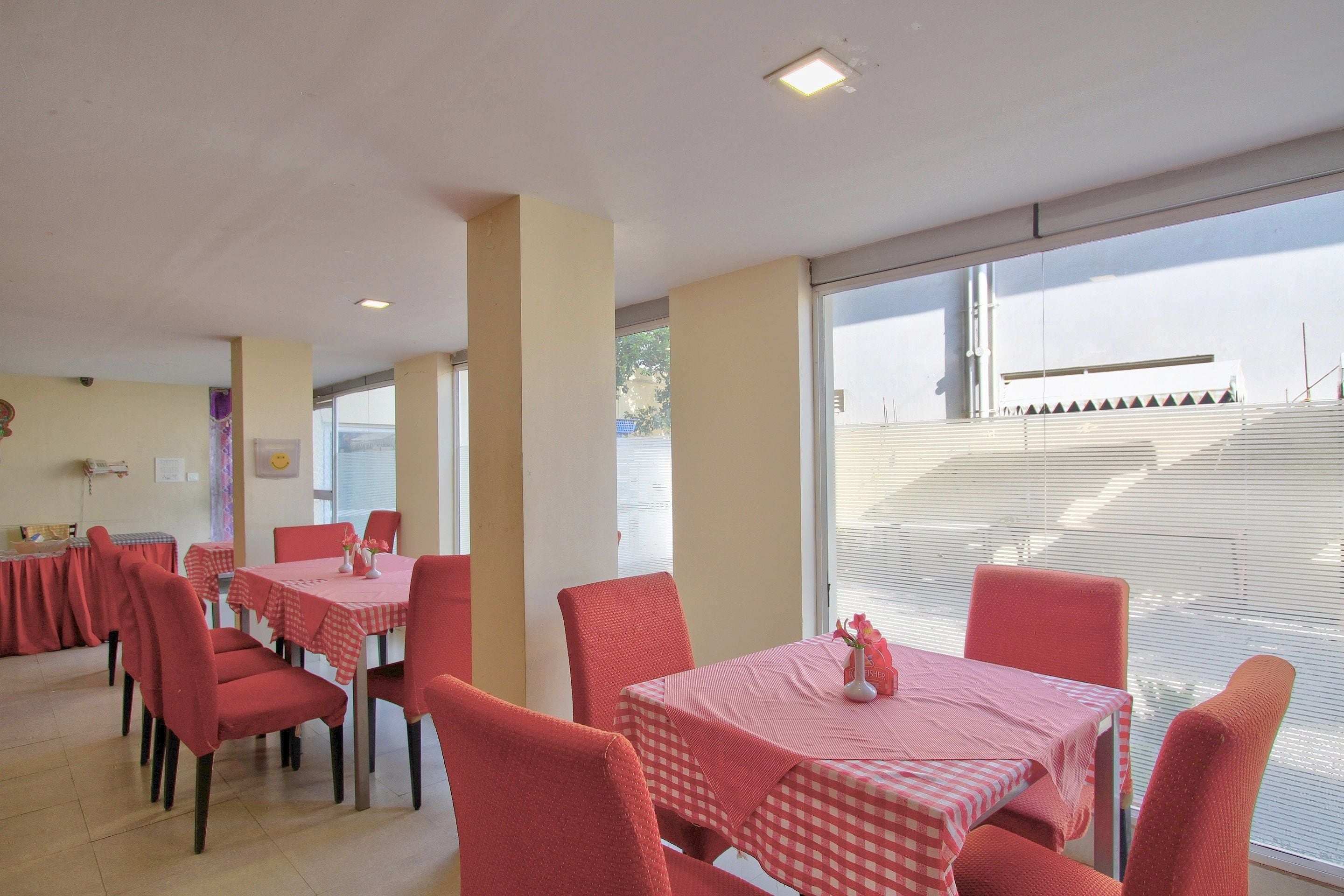 A dining area with tables and chairs, large windows, and a view of the outside.