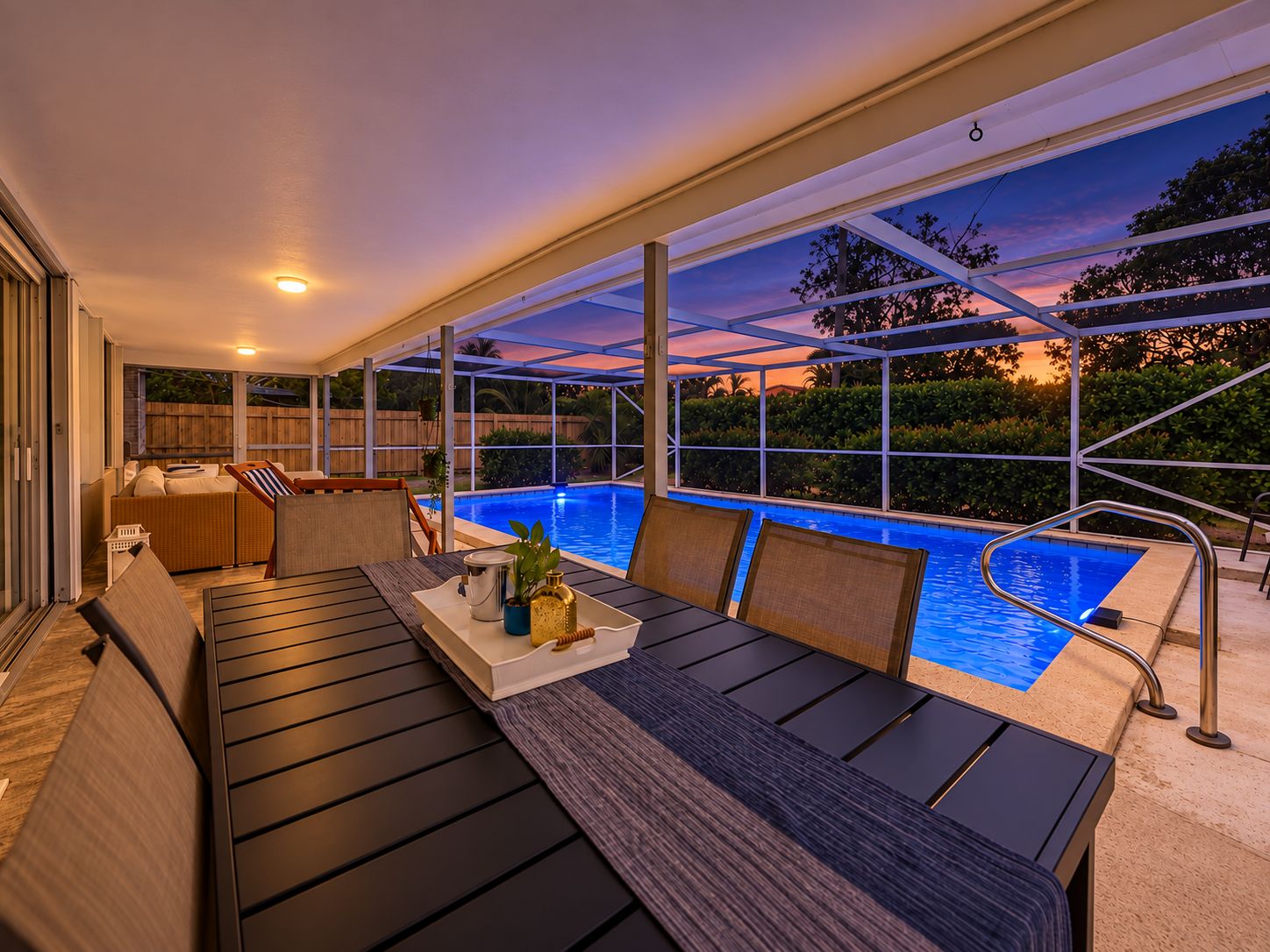 A poolside area with a covered seating area, a table with chairs, and a view of the pool.