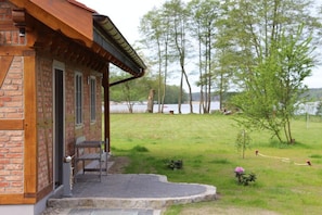 A brick building with a porch and a view of a lake. - Holiday home with 2 bedrooms (Pelzkuhl OT Strasen)