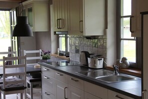 A kitchen with white cabinets, a black countertop, a sink, and a window with a view of greenery. - Holiday home with 2 bedrooms (Pelzkuhl OT Strasen)