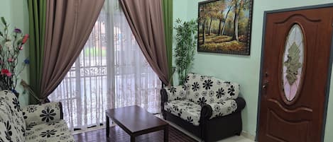A living room with a sofa, a table, and a door with a decorative glass panel.