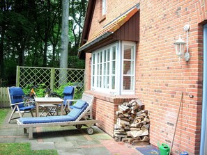 A brick house with a patio area featuring a table, chairs, and a lounge chair. - Holiday Home at the spa Park 1a (Wyk auf Foehr)