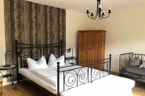 A bedroom with a metal bed frame, a wooden wardrobe, a small bedside table with a lamp, and a chandelier. - Müritz-Hof Knust - Farm (Klink \/ Sembzin)
