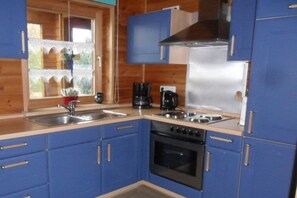 A kitchen with blue cabinets, a stainless steel sink, a stove, and a coffee maker. - Holiday home in Rechlin with swimming pool (Rechlin)