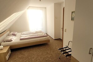 A single bed with a headboard, a bedside table with a lamp, a window with sheer curtains, a door, and a wall-mounted rack. - Holiday home in Ware with Wi-Fi and parking (Ware)
