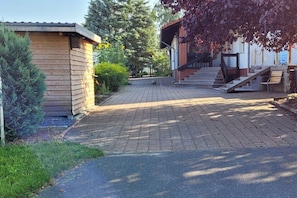 A paved driveway leading to a building with a staircase and a small wooden structure to the left. - Holiday home in Ware with Wi-Fi and parking (Ware)