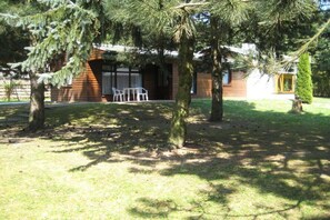 Una cabana de fusta amb un petit espai exterior, envoltada d'arbres.