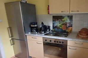 A kitchen with a stainless steel refrigerator, a coffee maker, a kettle, and a stove. - Langenthal Forestry House - House II (Braunsroda)
