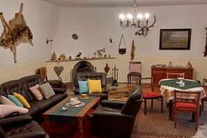 A cozy living room with a fireplace, leather sofas, a dining table, and various decorative items. - Langenthal Forestry House - House II (Braunsroda)