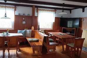 A cozy room with wooden furniture, a television, and a window with curtains. - Langenthal Forestry Lodge - House I (Braunsroda)