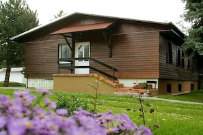A two-story wooden house with a balcony, a front door, and a small porch area. - Langenthal Forestry Lodge - House I (Braunsroda)