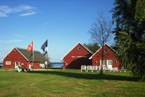 A red barn with a sign, a flag, and a bench in front. - "Domizil Fleesensee" (Untergöhren)