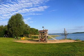 A playground with a slide and swings near a lake. - "Domizil Fleesensee" (Untergöhren)