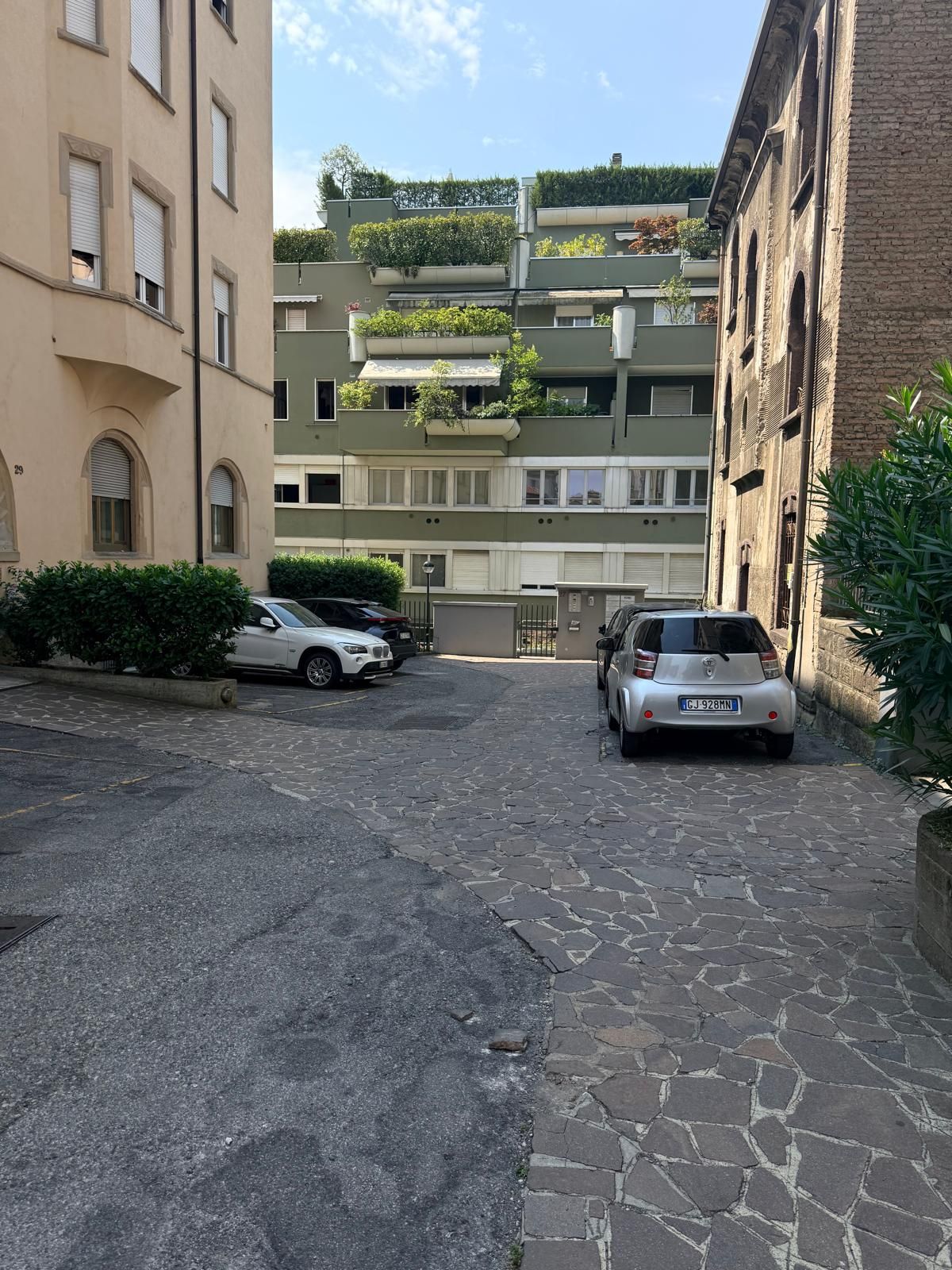 Eine schmale Straße mit parkenden Autos und Häusern an beiden Seiten.