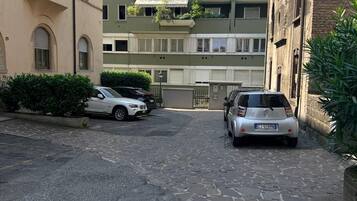 Eine schmale Straße mit parkenden Autos und Häusern an beiden Seiten.