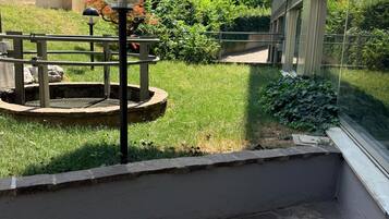 Un cortile con pavimento in pietra, un lampione in metallo e un piccolo giardino a forma circolare.